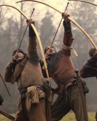 Close-up of medieval reenactors drawing longbows overhead in formation