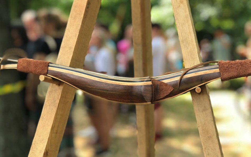 Close-up of a recurve bow's working limb and riser junction, showing the laminated limb construction