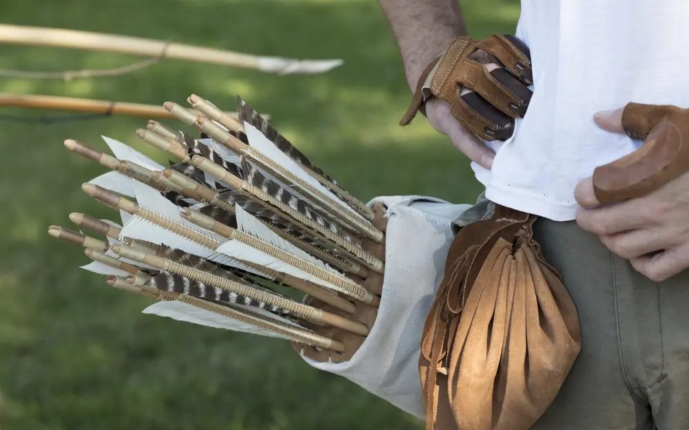 Traditional archer with a back quiver of wooden, feather-fletched arrows and a shooting glove