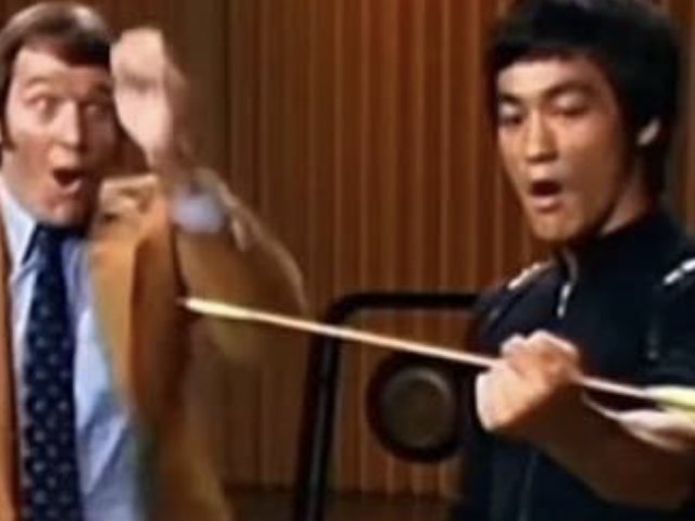 A film still of a martial artist snatching an arrow out of the air in front of a startled onlooker