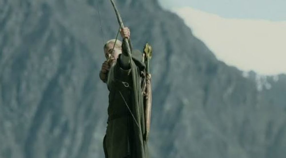 Elven archer at full draw against a mountain backdrop, bow limbs fully loaded
