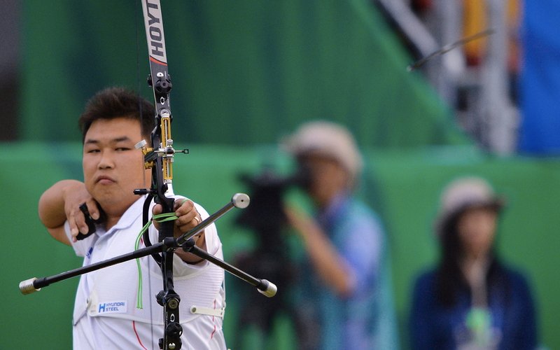 A recurve archer at full draw in competition, bow arm extended toward the target