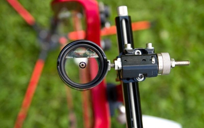 A compound bow drawn at a target, seen from behind the shooter