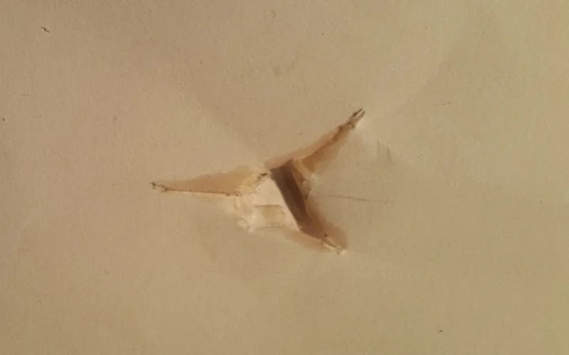 A tear through paper left by an arrow, showing nock-high flight